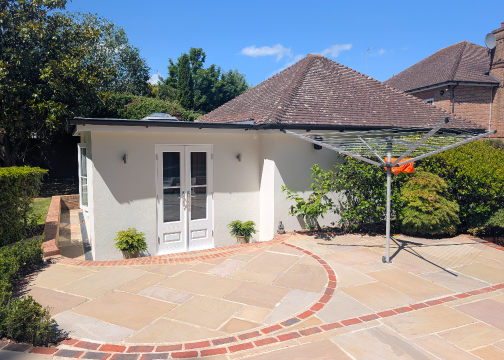 Small white garden building, paved patio, sunny day