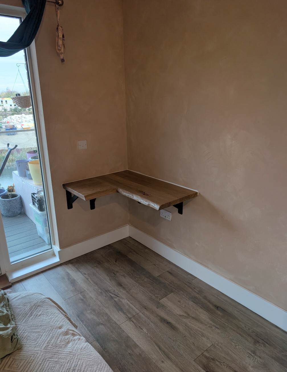 A small, corner-mounted wooden desk