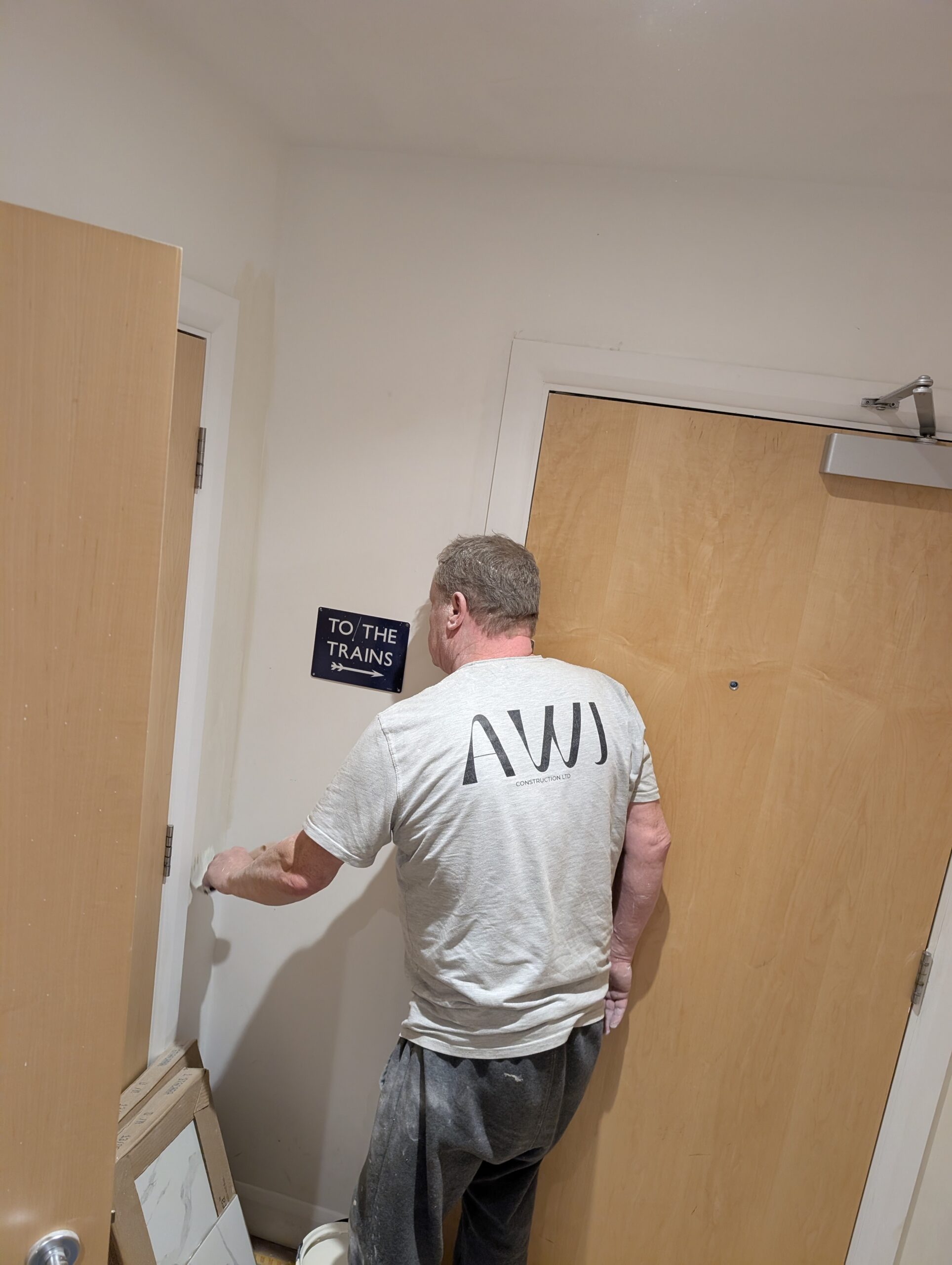 Man in hallway near 'To the Trains' sign
